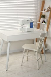 Sewing machine on white desk near chair indoors