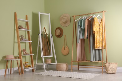 Photo of Modern dressing room interior with clothing rack and mirror near light green wall