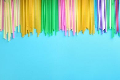 Photo of Colorful plastic drinking straws on light blue background, flat lay. Space for text