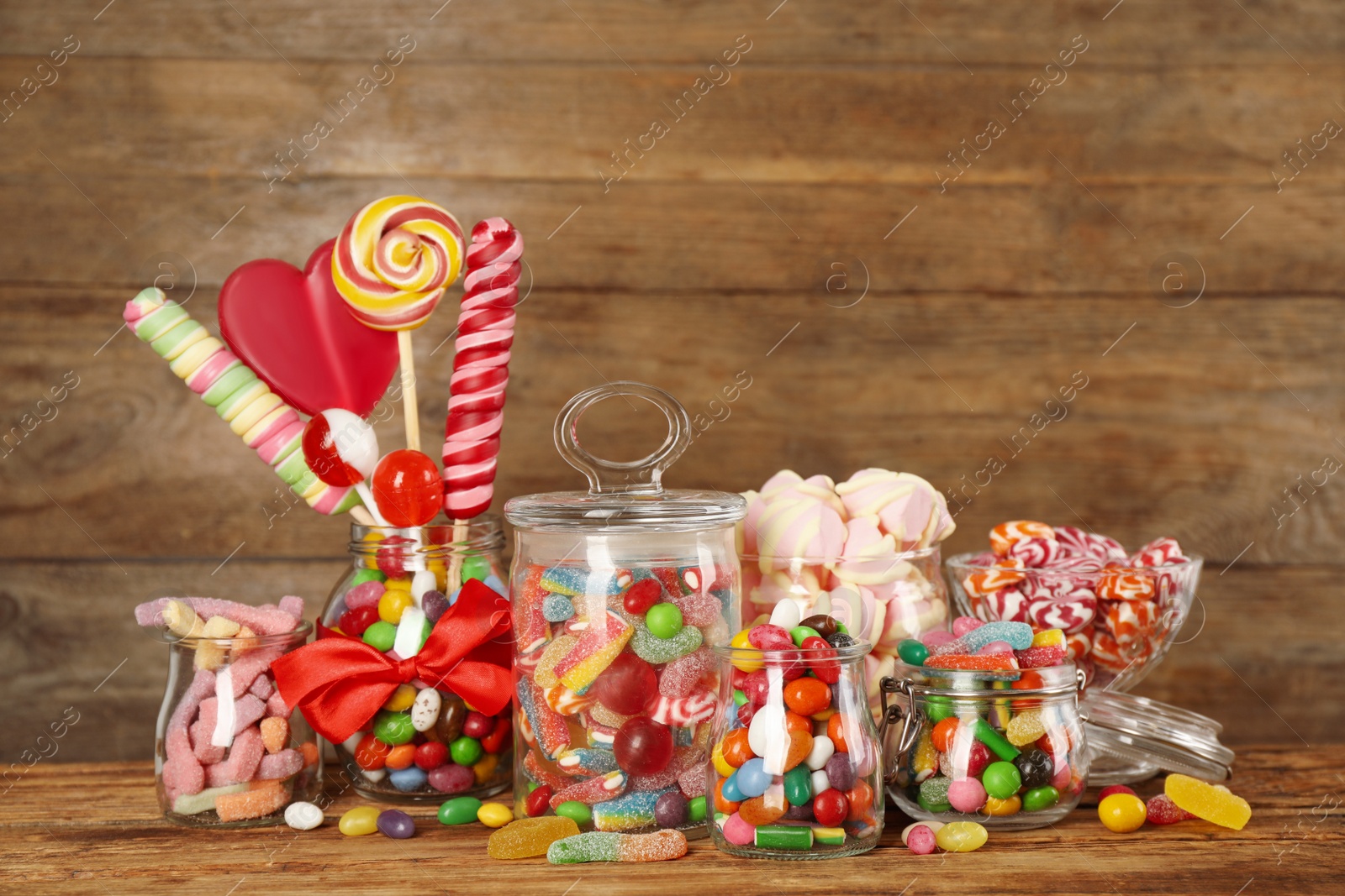 Photo of Jars with different delicious candies on wooden table