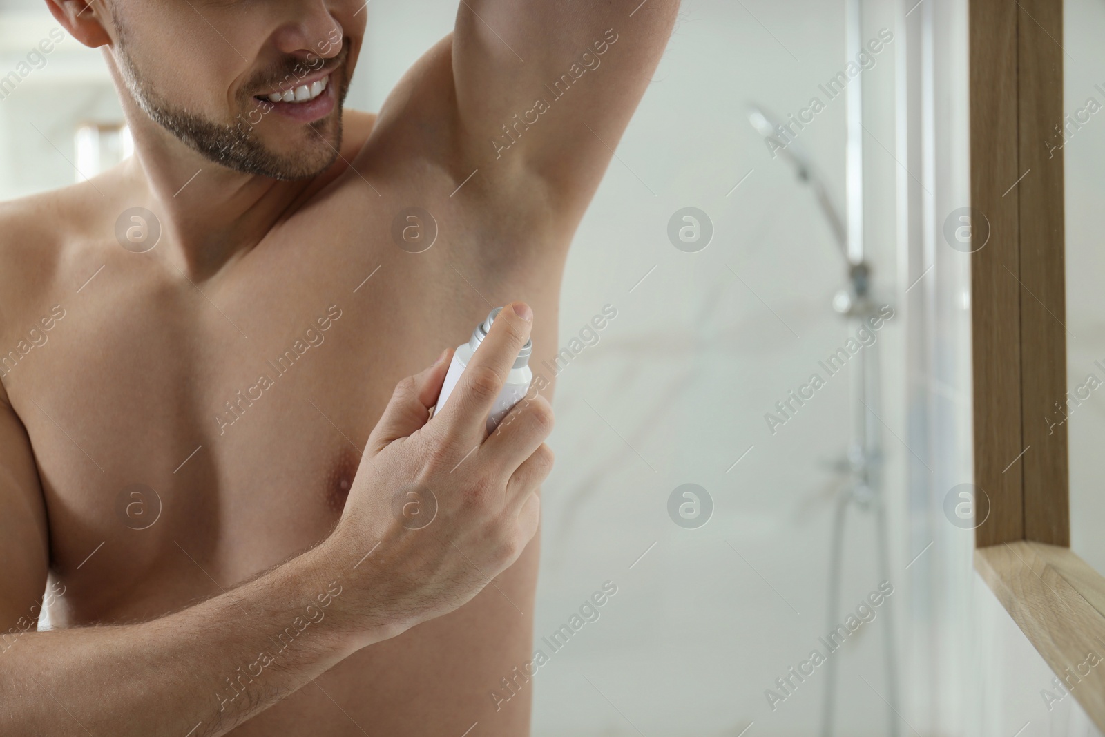 Photo of Man applying deodorant in bathroom, closeup. Space for text