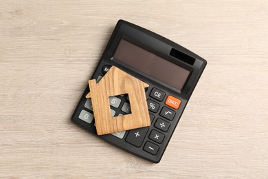 Photo of Mortgage concept. House model and calculator on wooden table, top view