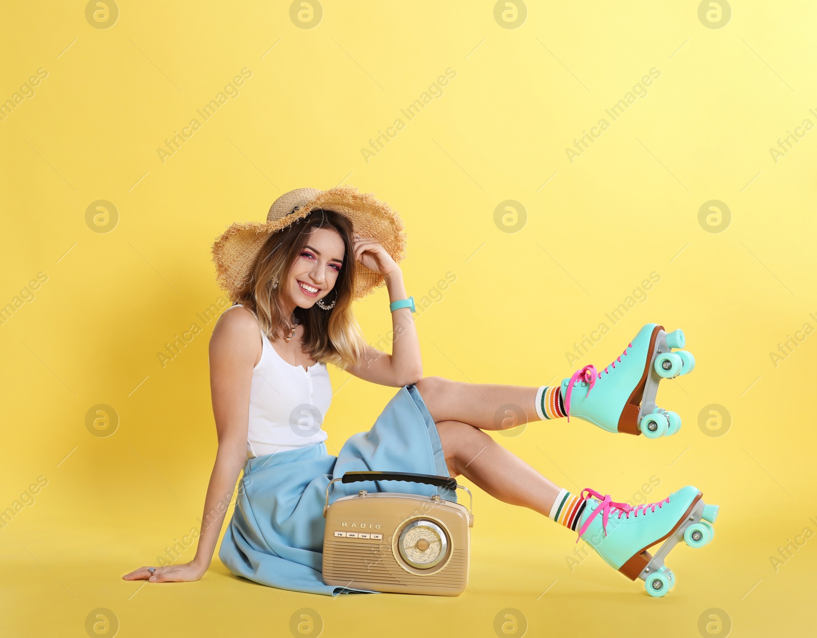 Photo of Young woman with roller skates and retro radio on color background