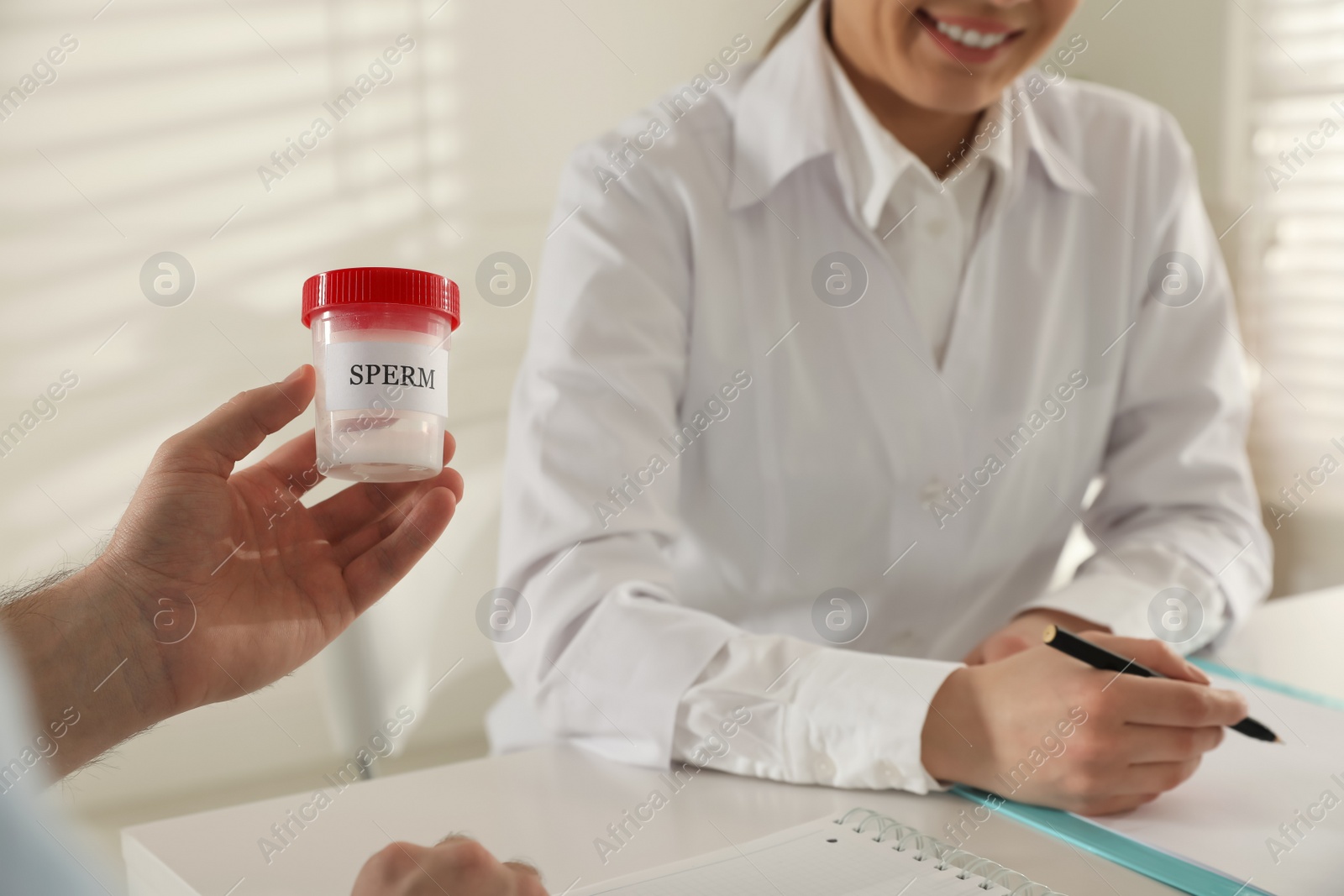 Photo of Donor giving container of sperm to doctor in hospital, closeup