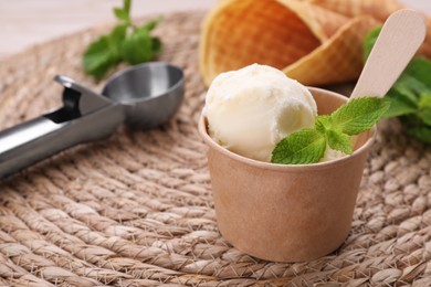 Paper cup with ice cream and mint leaves on wicker mat. Space for text