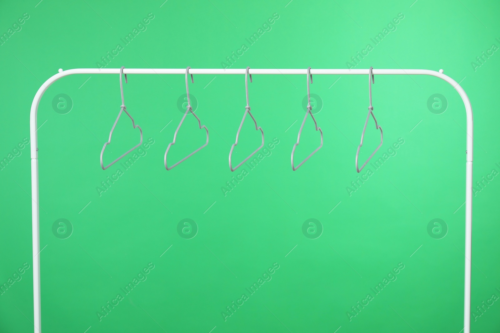 Photo of Empty clothes hangers on rack against green background