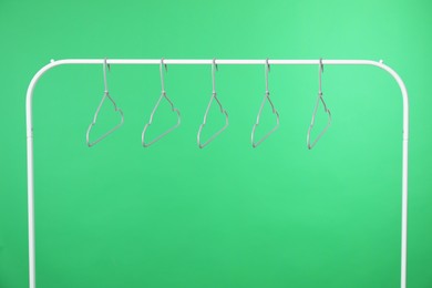 Photo of Empty clothes hangers on rack against green background