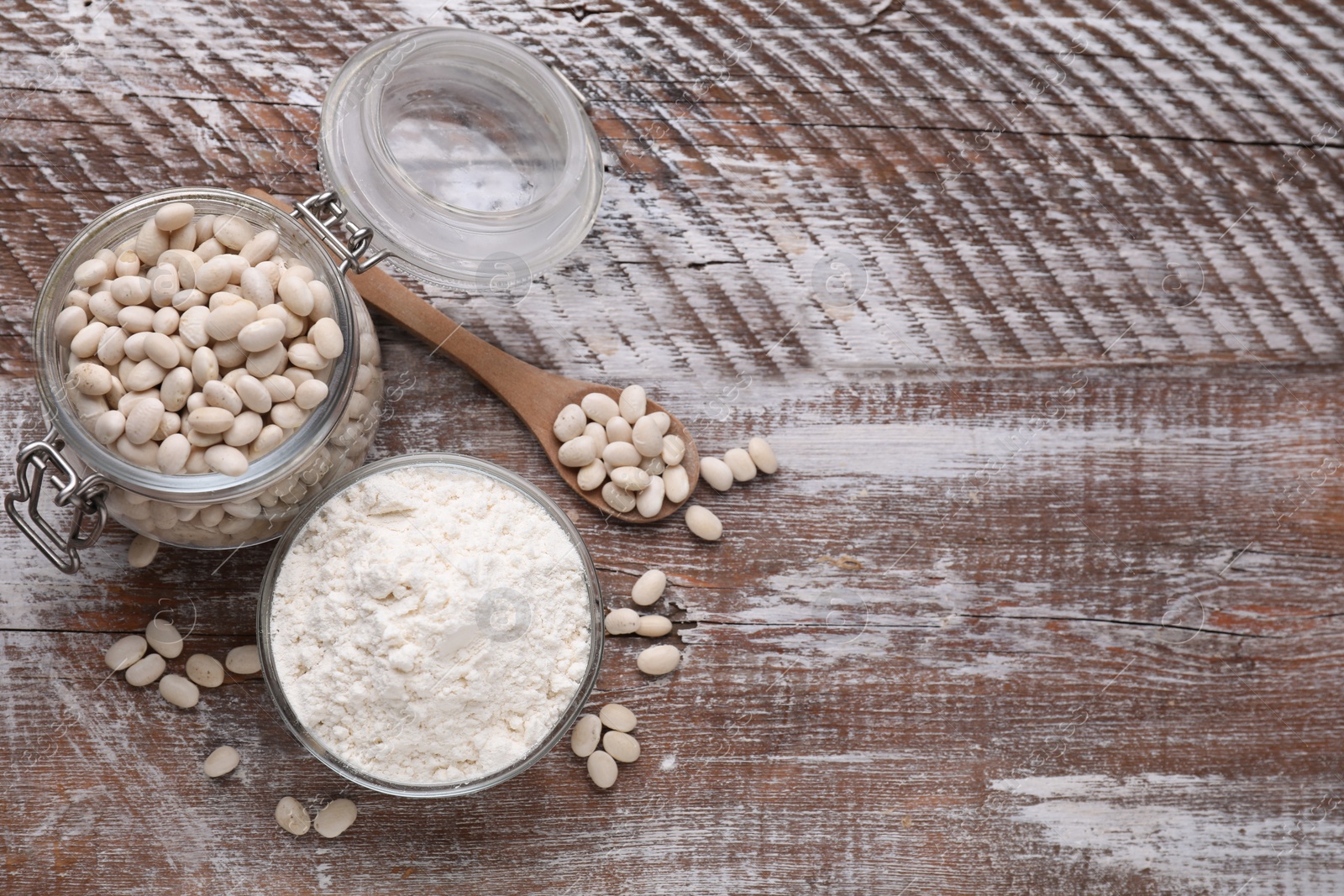 Photo of Bean flour and seeds on wooden table, flat lay. Space for text