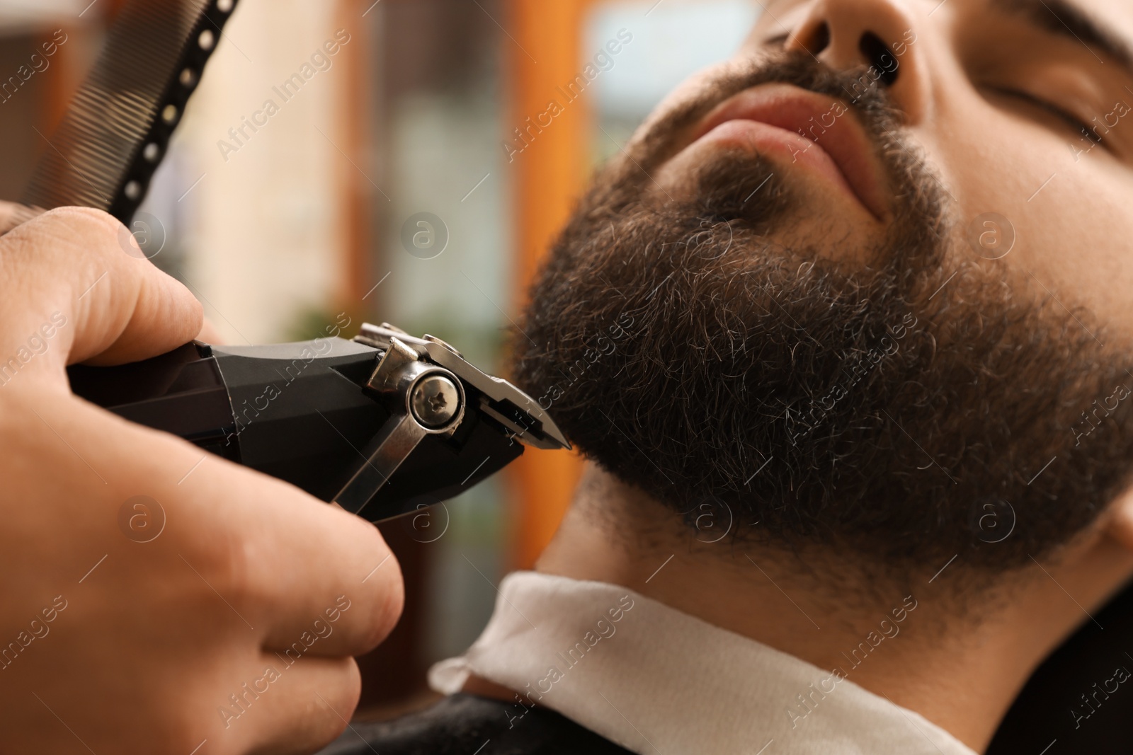 Photo of Professional hairdresser working with client in barbershop, closeup