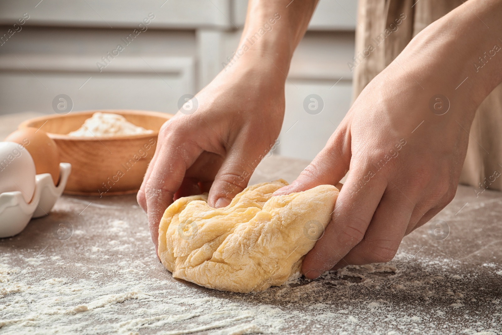 Photo of Woman kneading dough for pasta at table