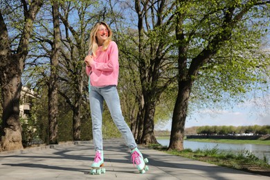 Photo of Beautiful young woman roller skating outdoors on sunny day