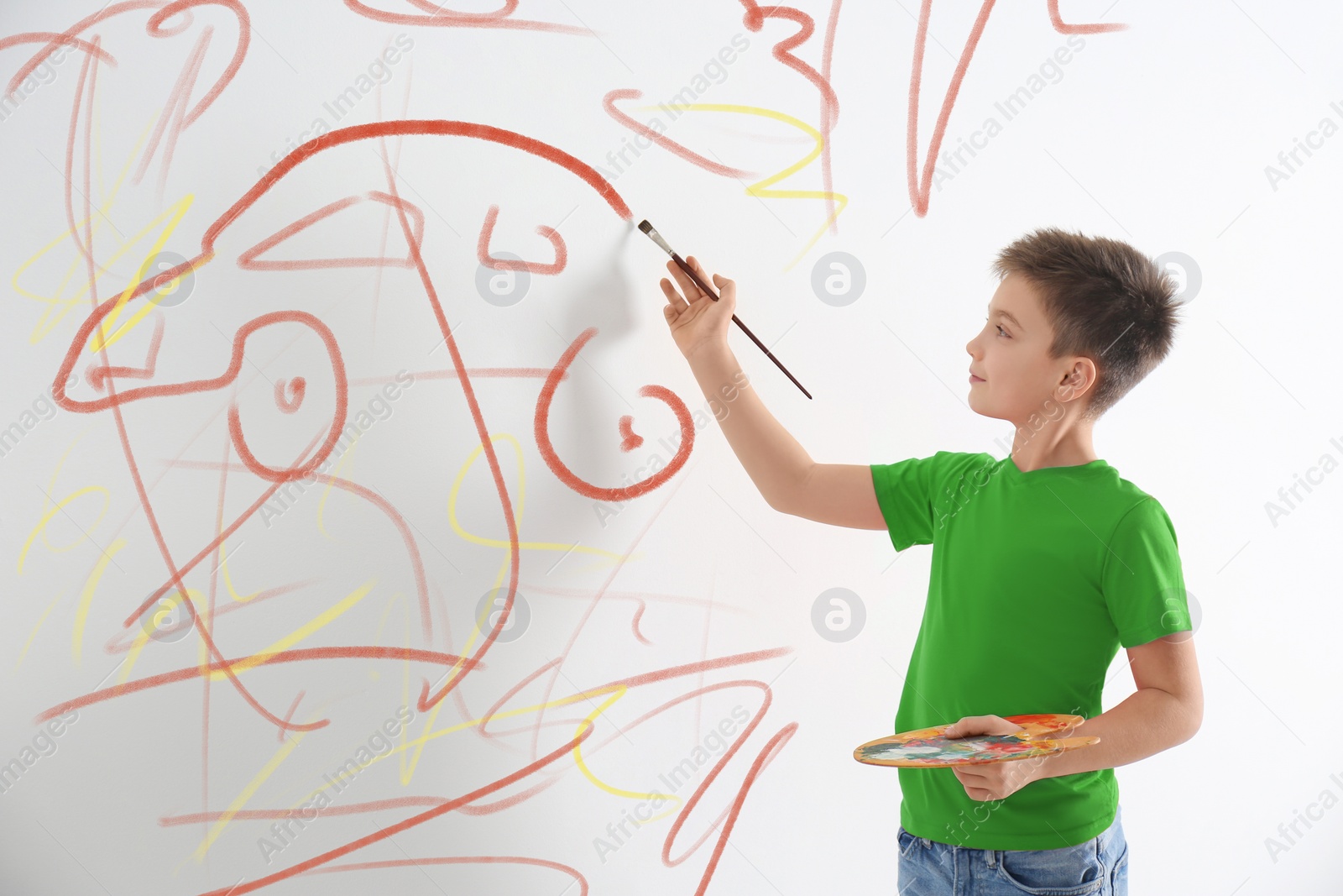 Image of Little child drawing scribbles on white wall indoors