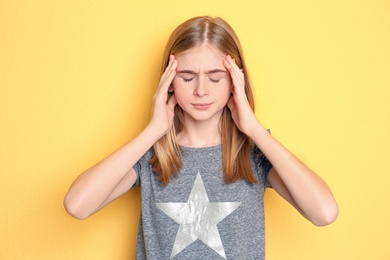 Teenage girl suffering from headache on color background