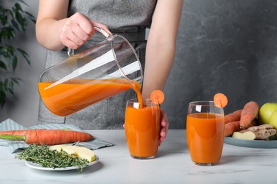 Photo of Woman pouring carrot juice from jug into glass, closeup
