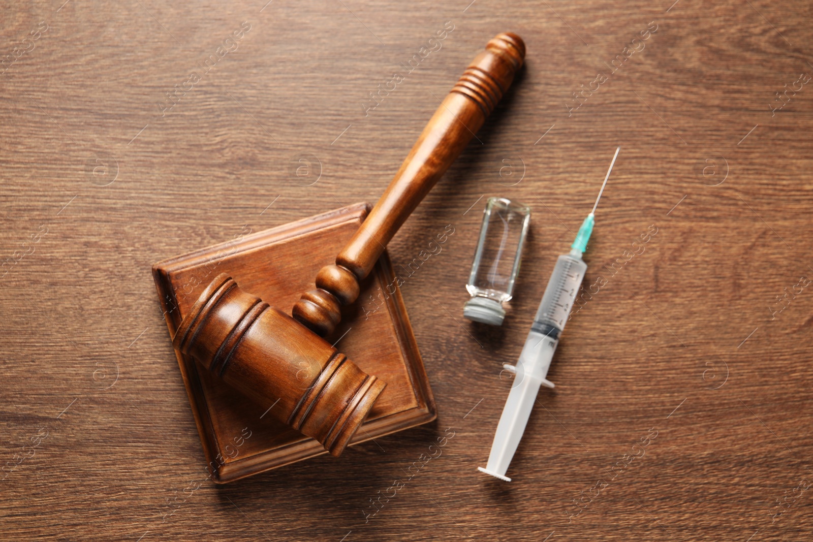 Photo of Law concept. Gavel, syringe and glass vial on wooden table, top view