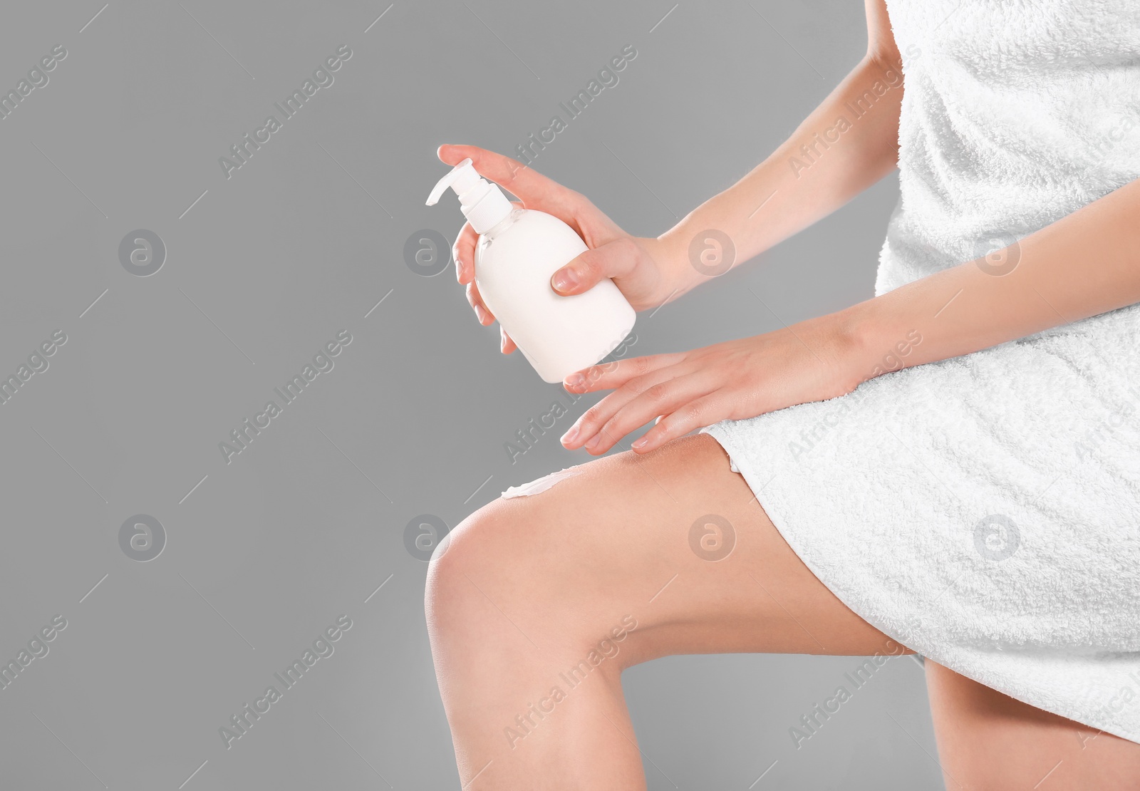 Photo of Young woman with bottle of body cream on color background