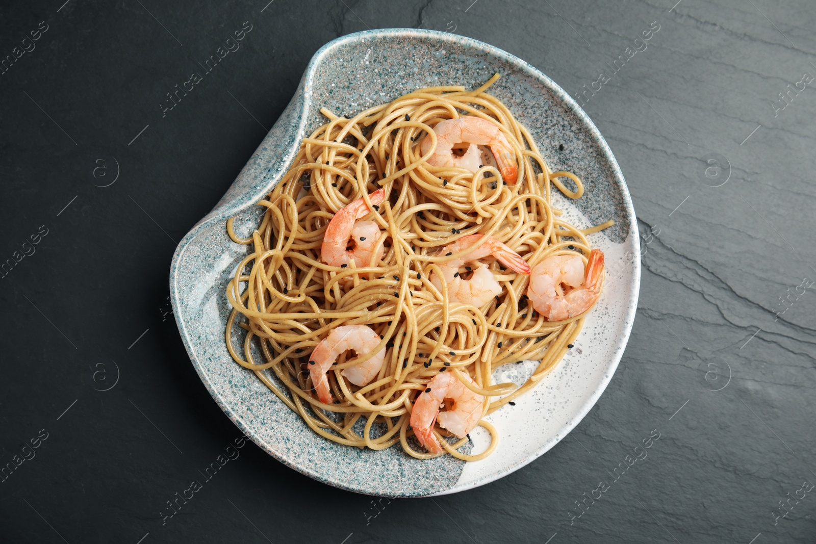 Photo of Plate of tasty buckwheat noodles with shrimps on black table, top view