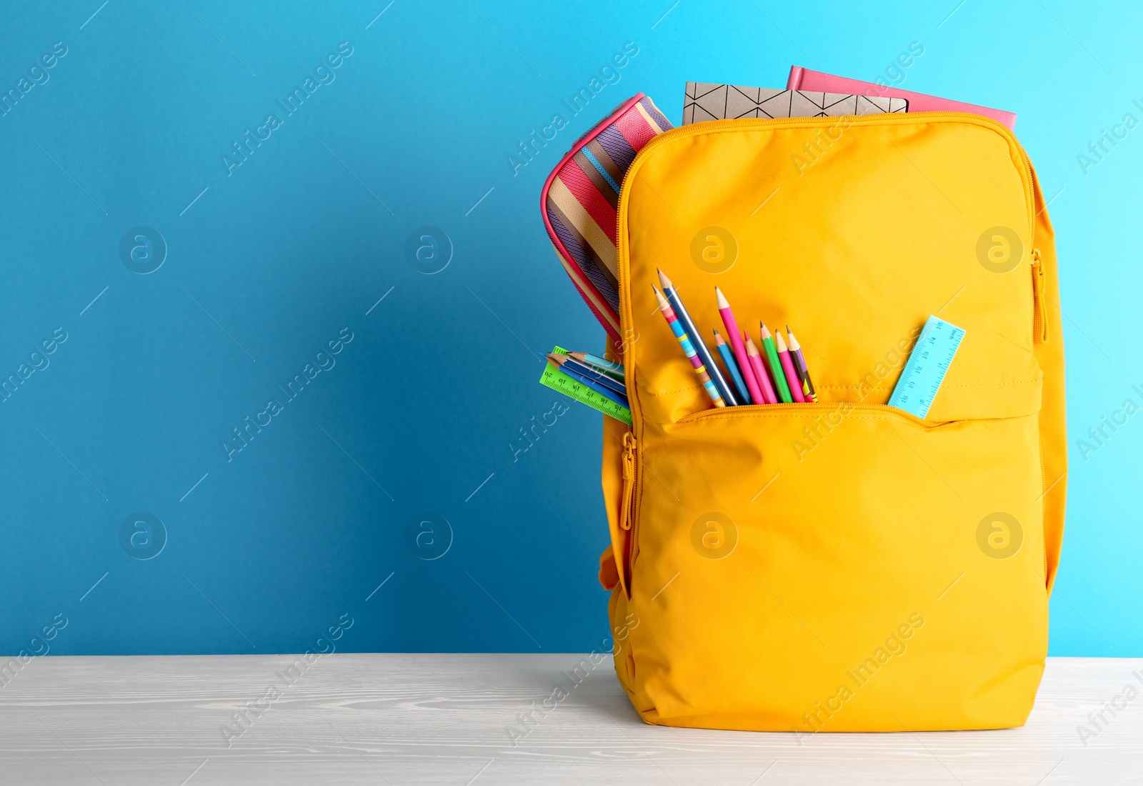 Photo of Backpack with different colorful stationery on table. Back to school