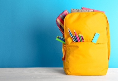 Photo of Backpack with different colorful stationery on table. Back to school