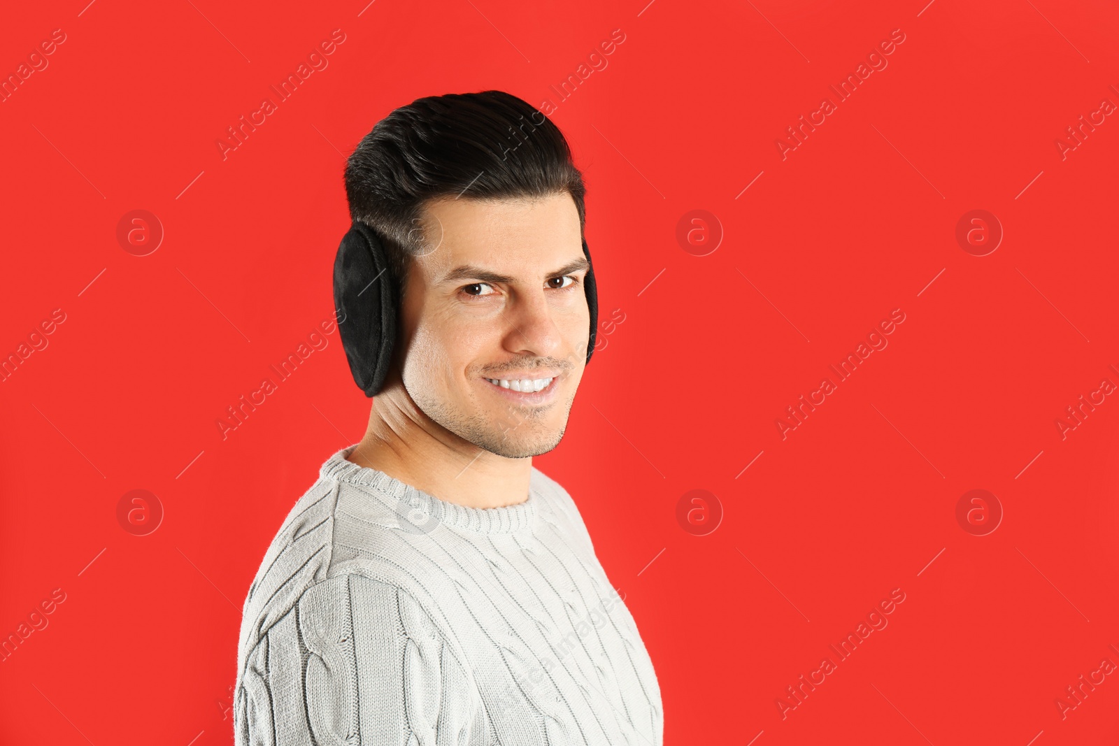 Photo of Man wearing stylish earmuffs on red background. Space for text