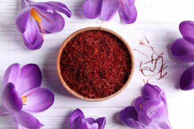 Photo of Dried saffron and crocus flowers on white wooden table, flat lay