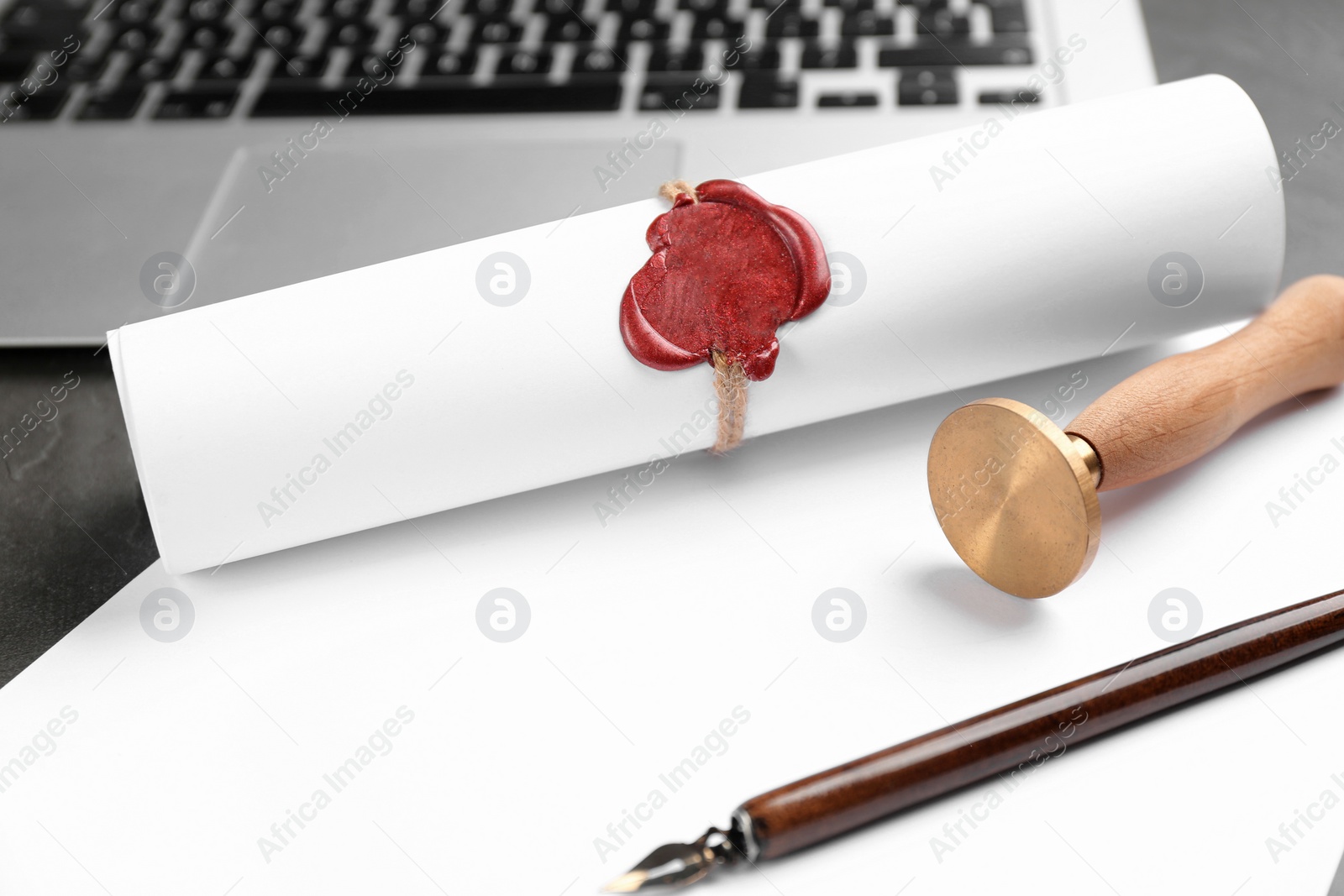 Photo of Notary's public pen and sealed document near laptop on grey stone table