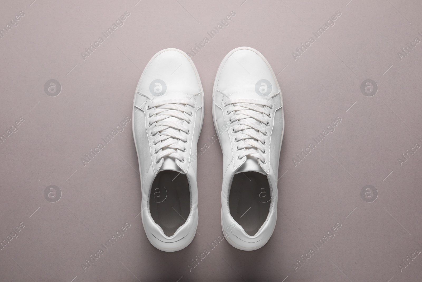 Photo of Pair of stylish white sneakers on grey background, top view