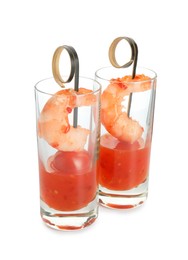 Photo of Tasty canapes with shrimps, tomatoes and sauce in shot glasses isolated on white