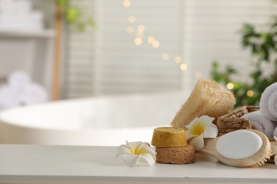 Photo of Composition with different spa products and plumeria flowers on white table in bathroom. Space for text