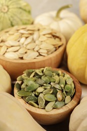 Bowls with seeds and fresh pumpkins on table, closeup