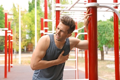 Young man having heart attack on sports ground