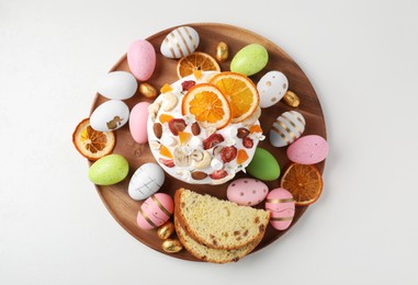 Photo of Traditional Easter cake with dried fruits and painted eggs on white table, top view