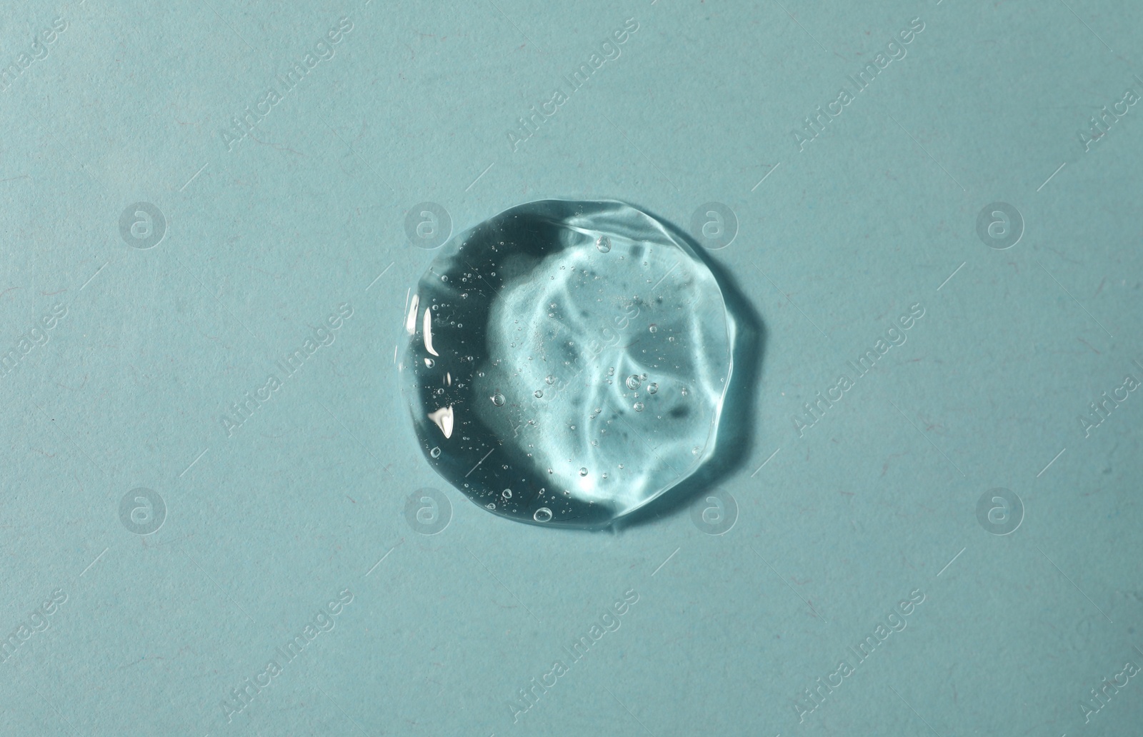 Photo of Sample of transparent cosmetic gel on light blue background, top view