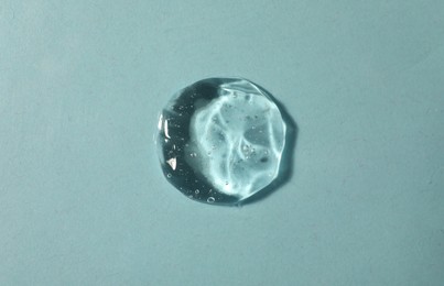 Photo of Sample of transparent cosmetic gel on light blue background, top view
