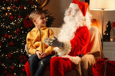 Photo of Merry Christmas. Little boy with Santa Claus in room