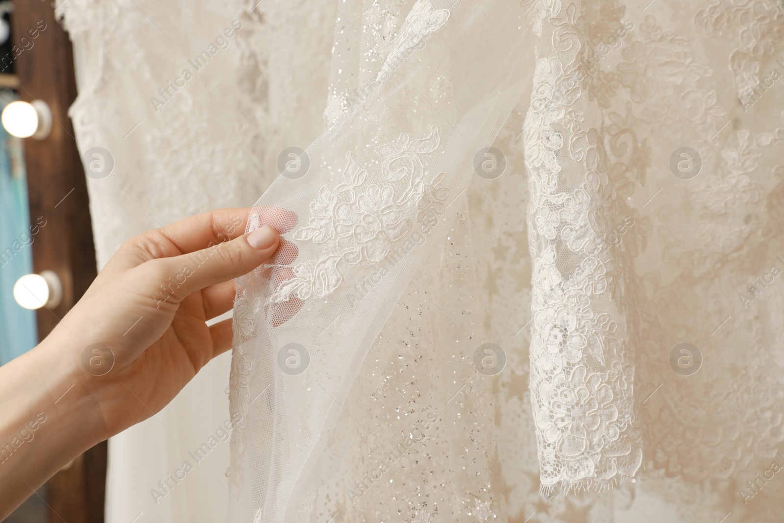 Photo of Young woman choosing wedding dress in salon, closeup