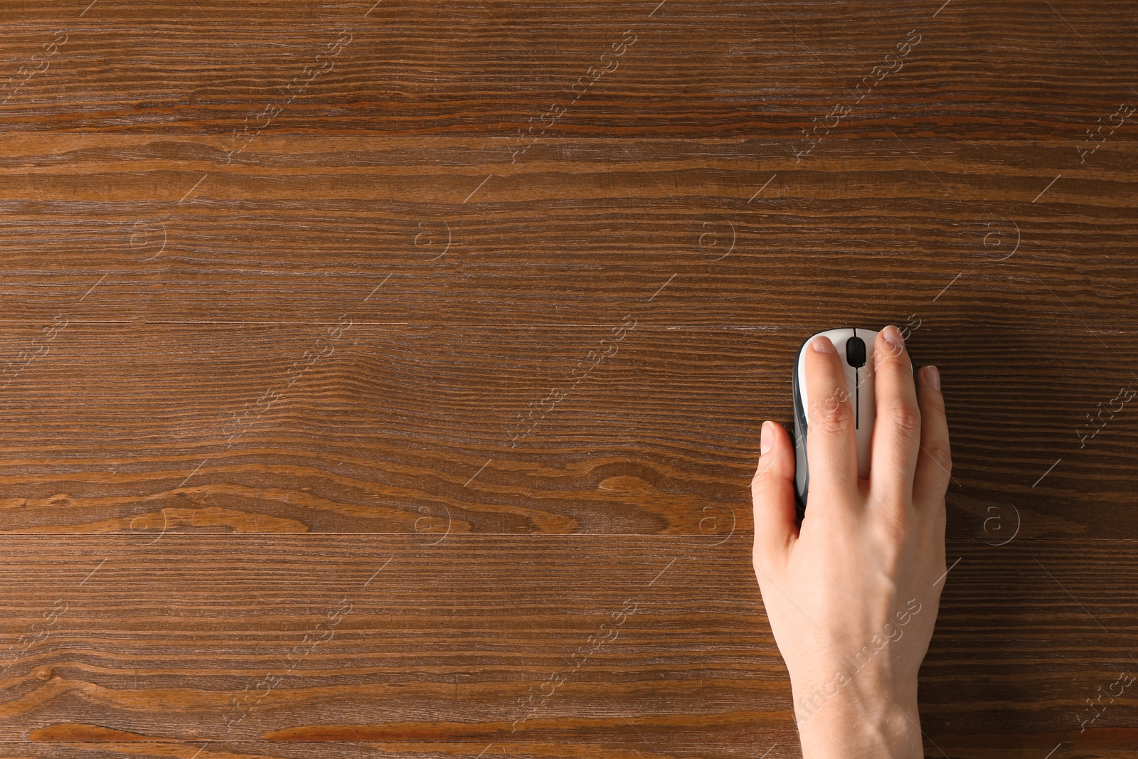 Photo of Woman using computer mouse on wooden background, top view. Space for text