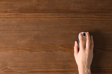 Photo of Woman using computer mouse on wooden background, top view. Space for text