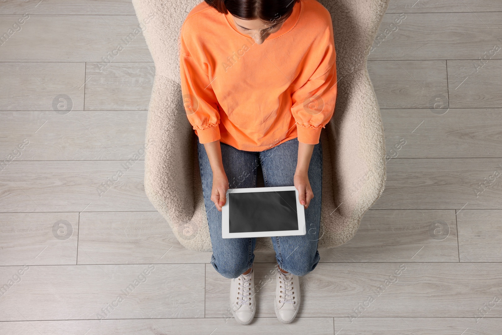 Photo of Woman working with tablet in armchair, top view