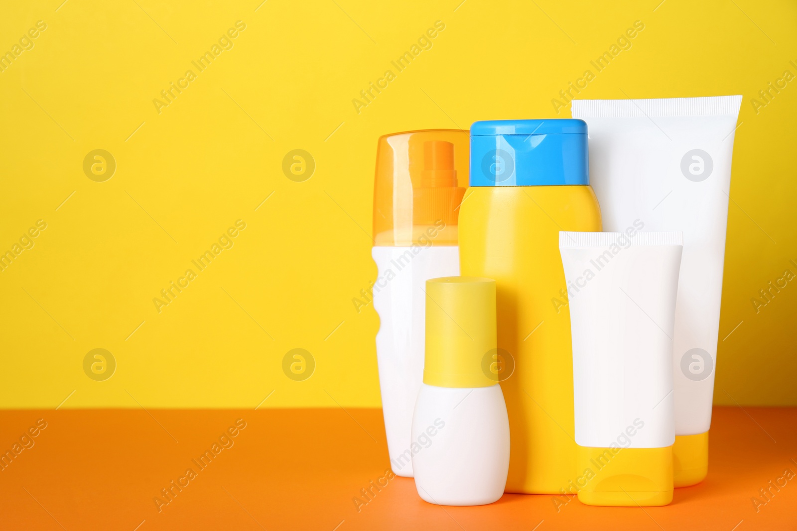 Photo of Different suntan products on color background. Space for text