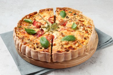 Tasty quiche with tomatoes, basil and cheese on light textured table, closeup