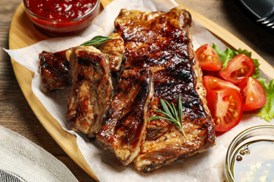 Photo of Delicious grilled ribs served on wooden table, closeup