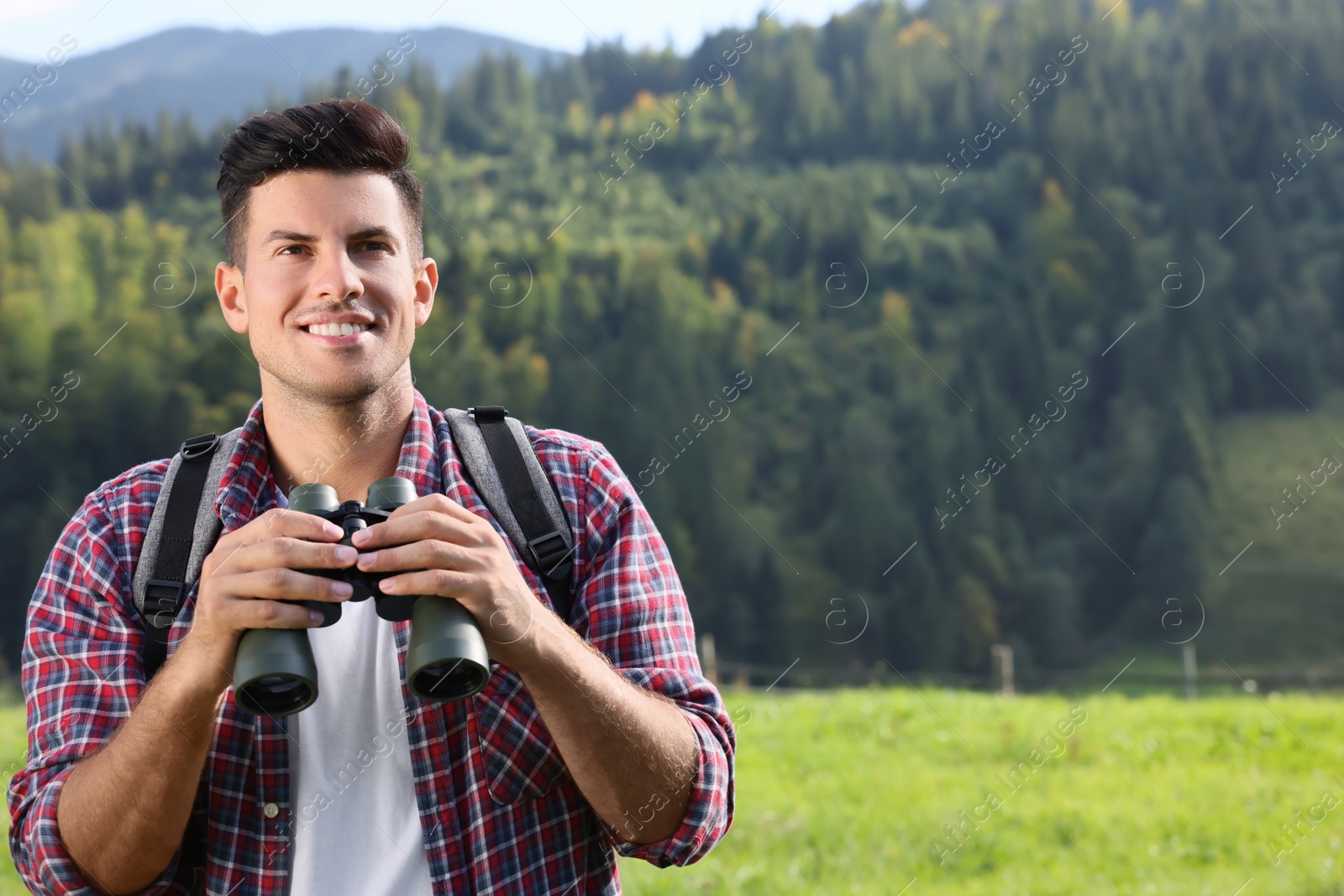 Photo of Man with backpack and binoculars in mountains