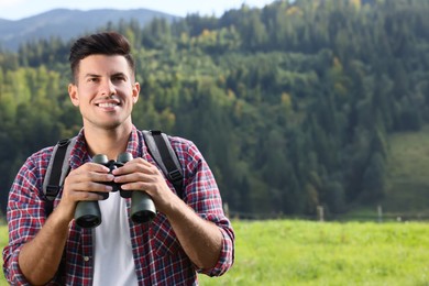 Photo of Man with backpack and binoculars in mountains