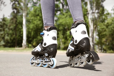 Woman with modern inline roller skates in city park, closeup