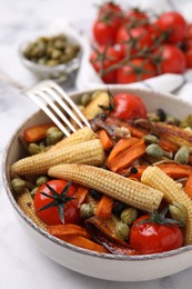 Photo of Tasty roasted baby corn with tomatoes and capers on white marble table, closeup
