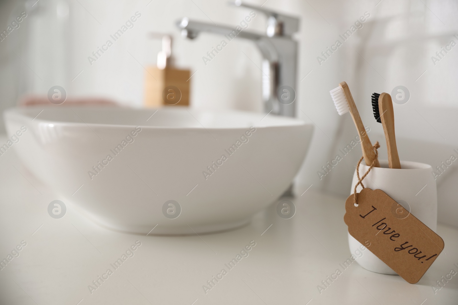 Photo of Tag with handwritten text I Love you on toothbrush in bathroom. Romantic message