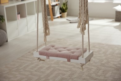 Photo of Beautiful swing in room. Stylish interior design