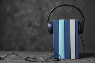 Photo of Modern headphones with hardcover books on table. Space for text