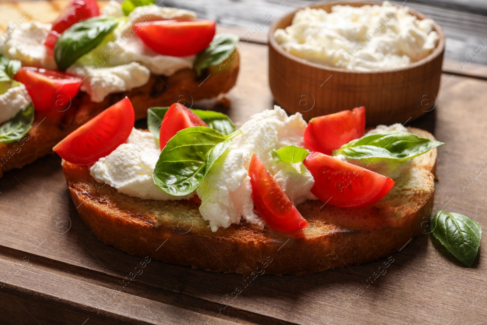 Photo of Toasted bread with tasty cream cheese and tomatoes on wooden board